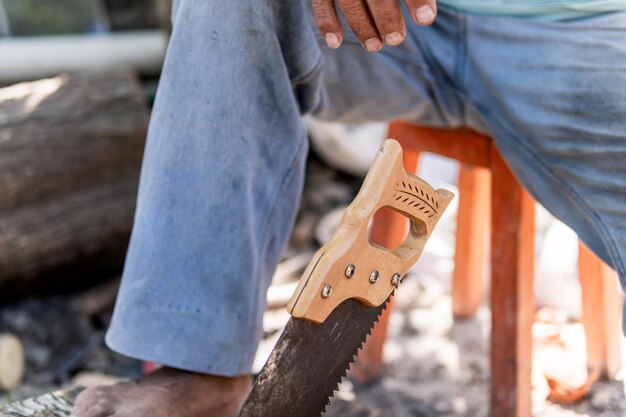 Photo old latino man chopping wood with a saw