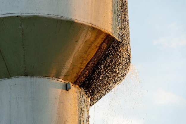 An old leaky water tower Water flows from a large iron barrel Broken metal construction