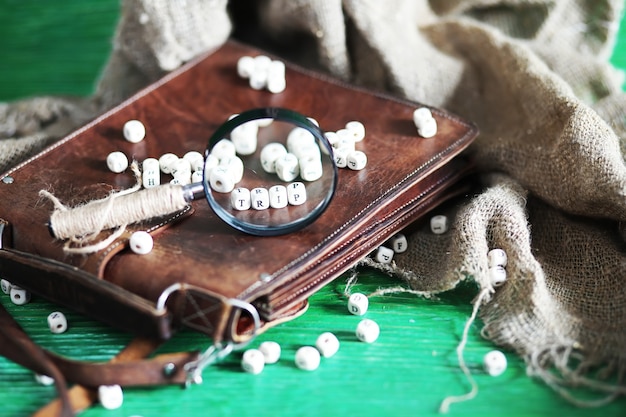 Old leather bag with a magnifying glass on a brown traveler wooden table background with copy space.