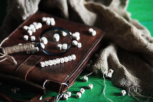 Old leather bag with a magnifying glass on a brown traveler wooden table background with copy space.