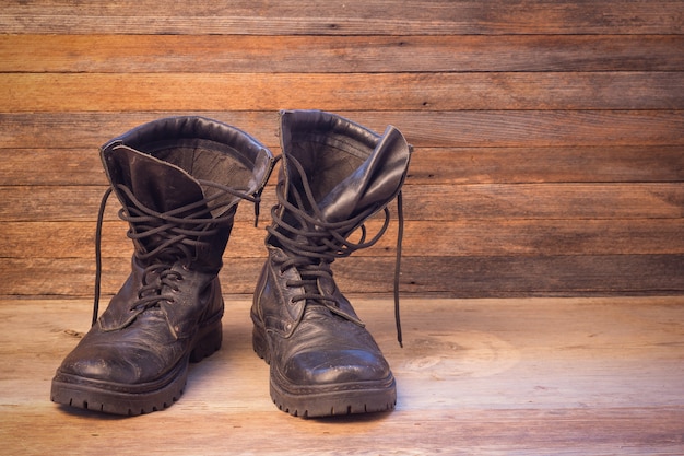 Old leather black male shoes ankle boots on a wooden background front view closeup