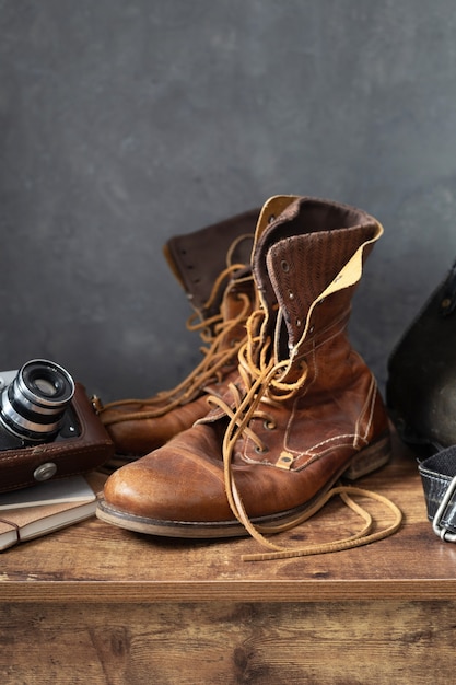 Old leather travel vintage boots shoes and bag at wooden table, with wall background texture