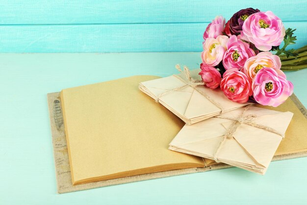 Old letters and book with flowers on wooden background