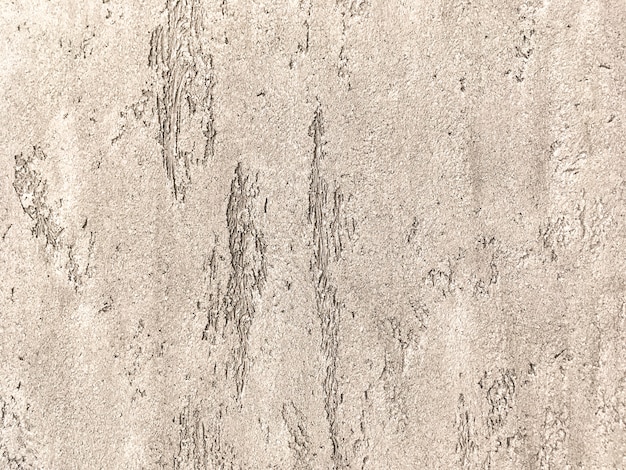 Old light brown wall covered with shabby uneven plaster. Texture of vintage bronze stone surface, closeup