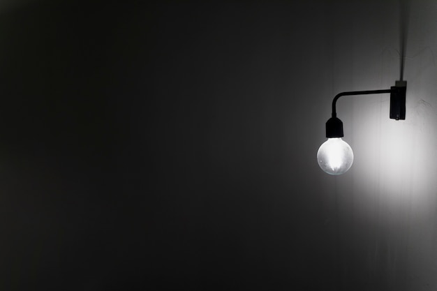 Foto una vecchia lampadina sul muro di cemento nel buio