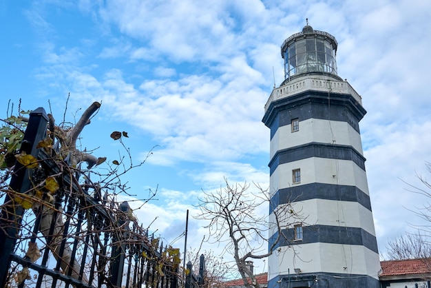 An old lighthouse under a blue partial cloudy sky.