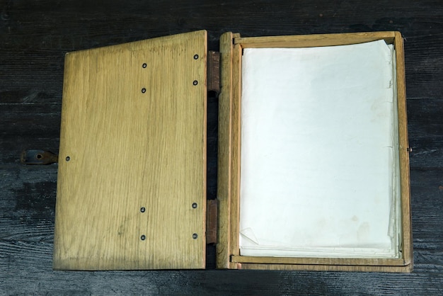 old log book in a wooden case with clasps on a black tabletop open