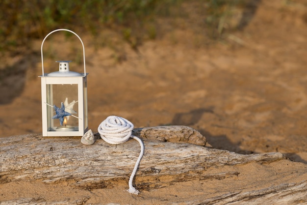 on the old log in a nautical style lantern, a shell and a nautical rope