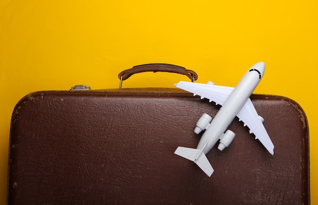 Old luggage and airplane figurine on yellow surface