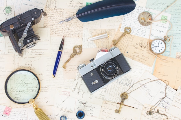 Old mails background with vintage watch, feather pen, camera and key