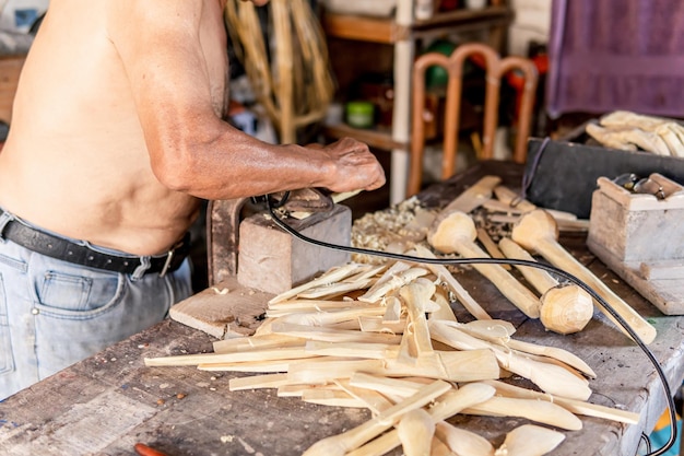 Old man carving wooden spoons in the house