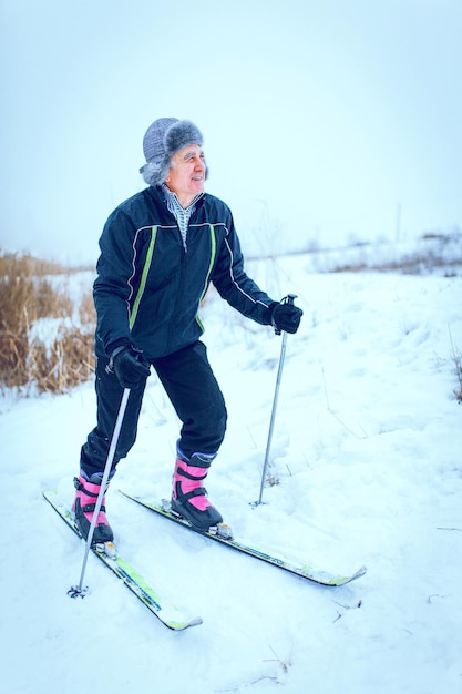 An old man exercises to improve his health by cross country skiing.