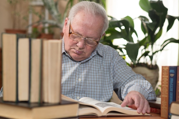 Old man or grandfather reading literature sitting at a desk in the office