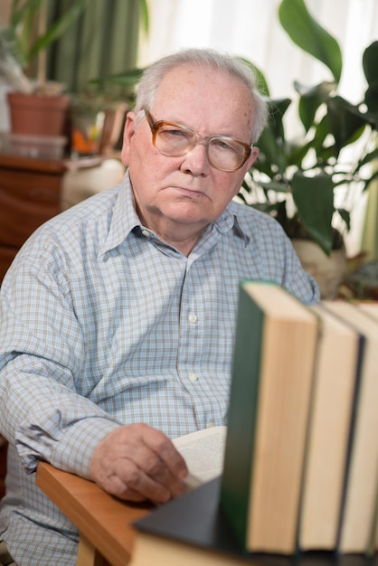 Old man or grandfather reading literature sitting at a desk in the office