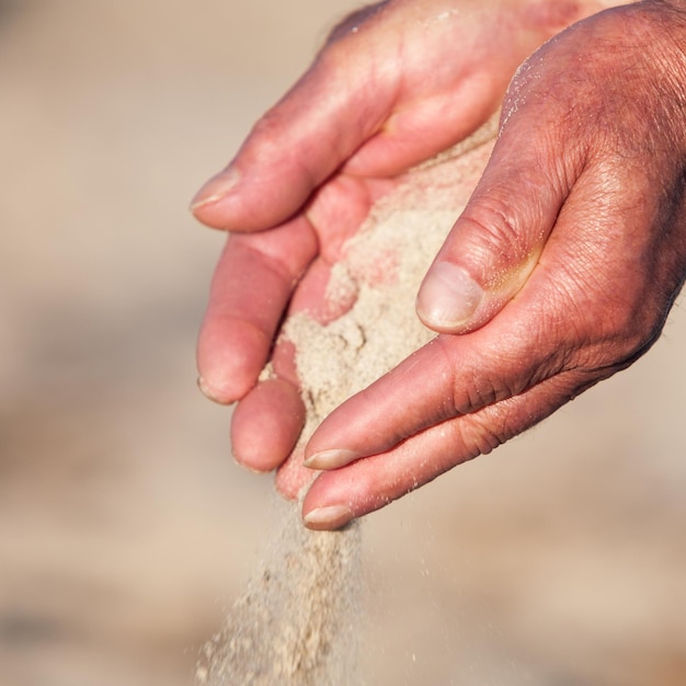 Old man hands holding and spilling sand