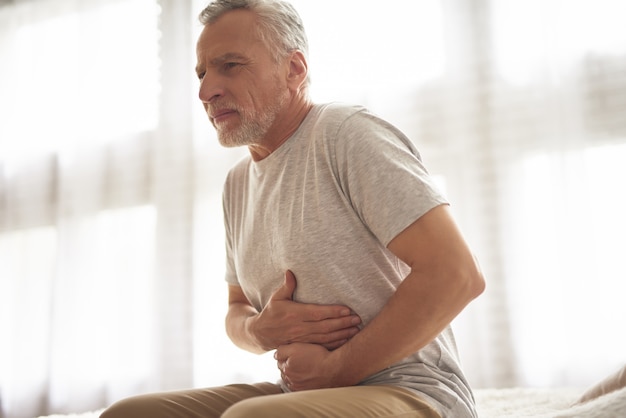 Photo old man holding belly stomach ache hurts patient.