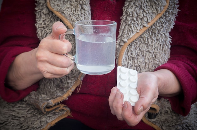 An old man holds an aspirin in his hands.