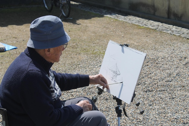 an old man is painting a picture in a park