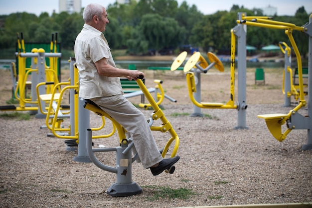 Photo old man making exercises on outdoor gym