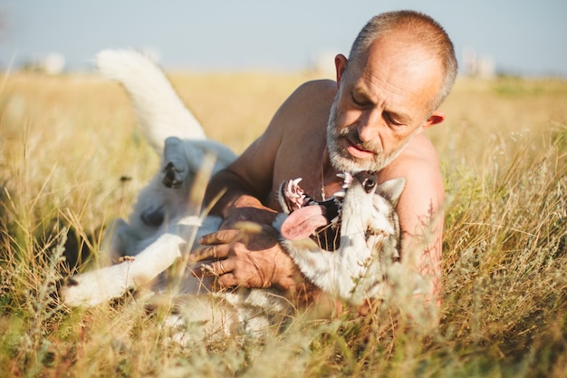 写真 彼の犬のシベリアンハスキーと遊ぶ老人