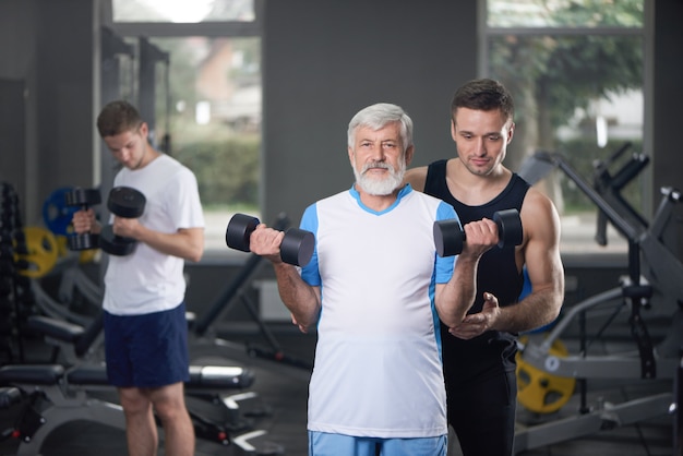 old man posing with dumbbells, coach training.