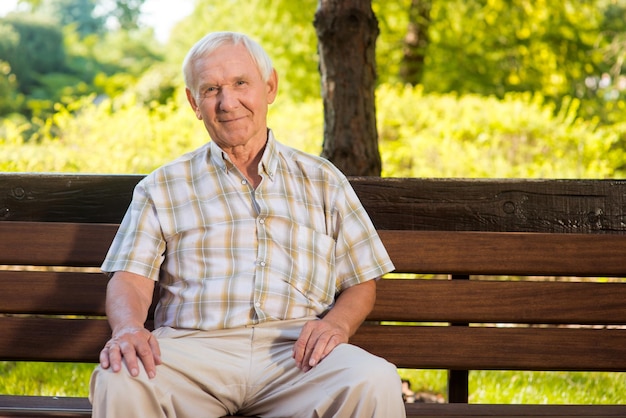 Old man sits on bench elderly guy is smiling he deserves a good rest all problems left behind