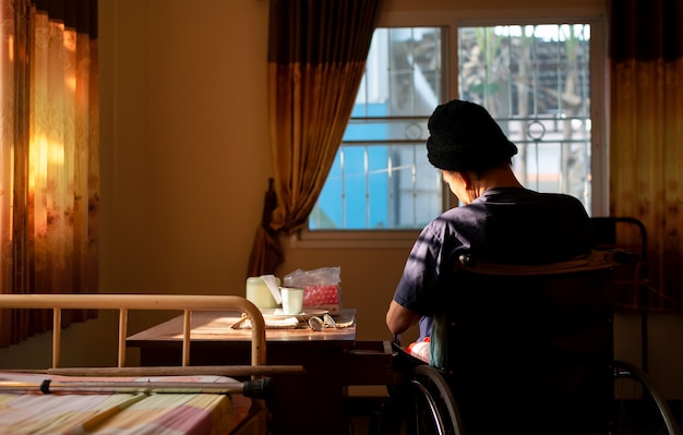 Old man sitting alone in a wheelchair at house 