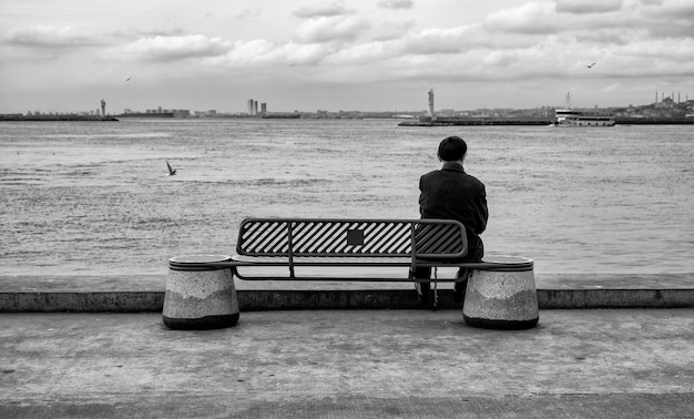 an old man sitting on a bench by the sea