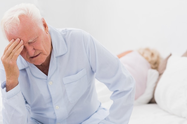 Old man suffering while woman sleeping 