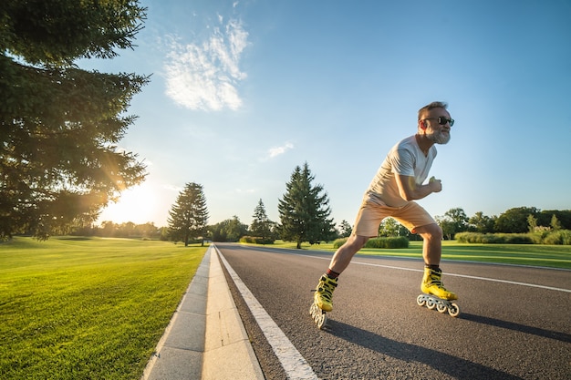 The old man in sunglasses rollerblading on the road