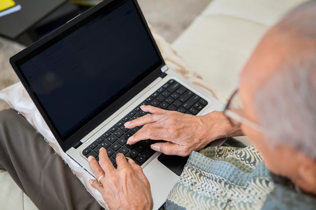 Old man typing on the laptop with blank screen