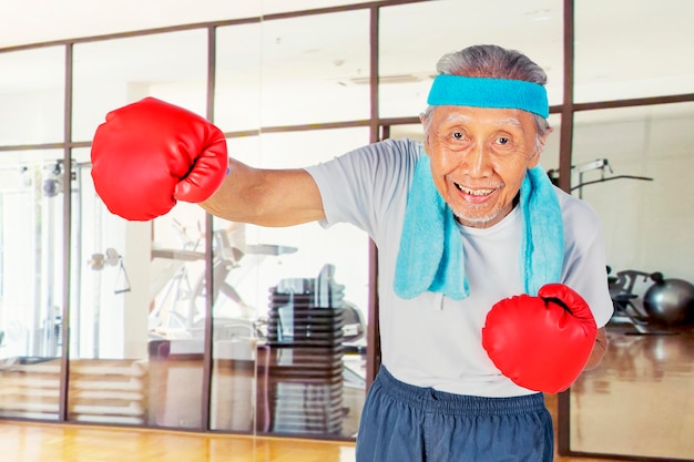 Old man wear boxing gloves while show his punch