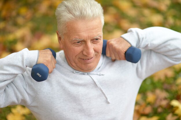 Old man with dumb bells at nature