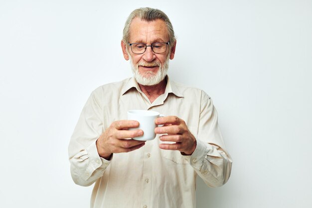 Old man with glasses shows a mug on a white background