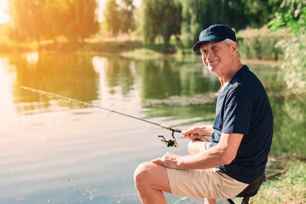 Old Man with Gray Hair Fishing on River in Summer.