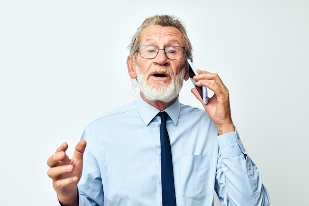 Old man with phone in studio on white background talking