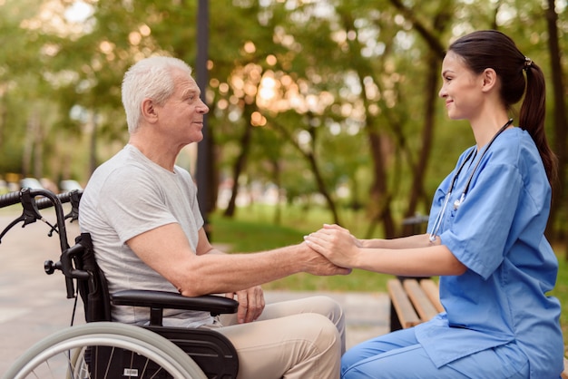 An old man with young nurse are holding hands