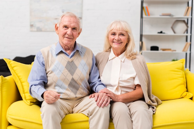 Old man and woman sitting on yellow sofa