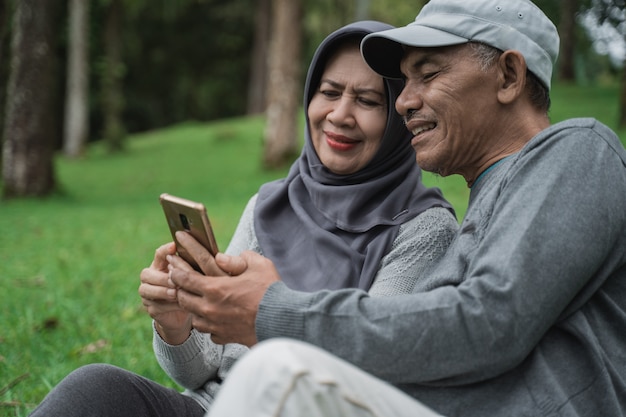 Uomo anziano e donna che utilizza telefono cellulare nel parco