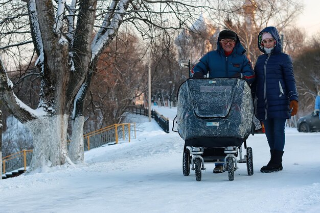 Old man and woman walk with a stroller in the winter