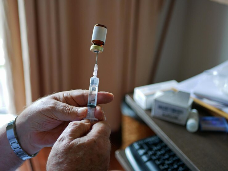 Photo old mans hands carefully pulling the medicine into the syringe by himself at home - self injecting