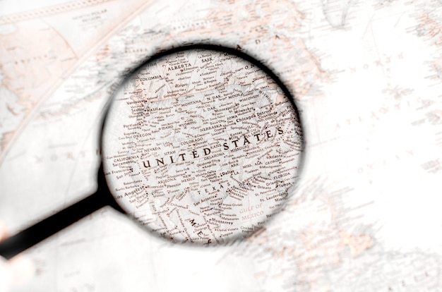 Photo old map with territory of united states of america and name of country is enlarged through a magnifying glass.