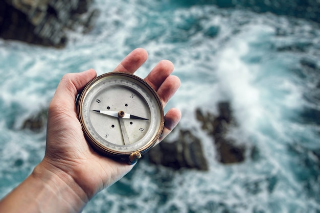 写真 海の背景に手に古い海洋コンパス