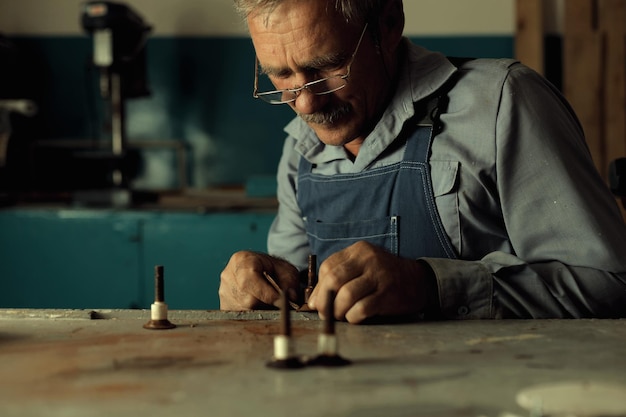 An old master with glasses works in a workshop