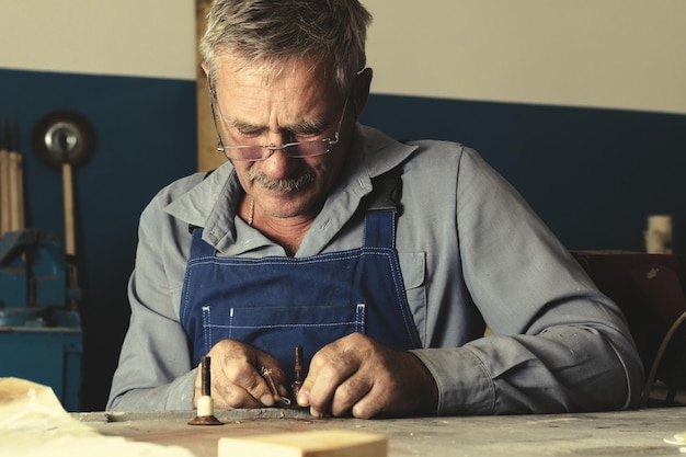 An old master with glasses works in a workshop