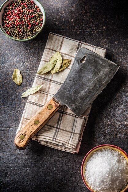 Old meat butcher on dark concrete board with spices salt and pepper.