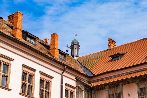 青い空を背景にした古い中世の建物。古代建築。赤い屋根瓦の家。