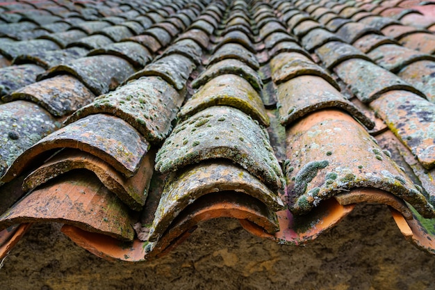 Old medieval house roof made with clay tiles aged by the passage of time. Spain.