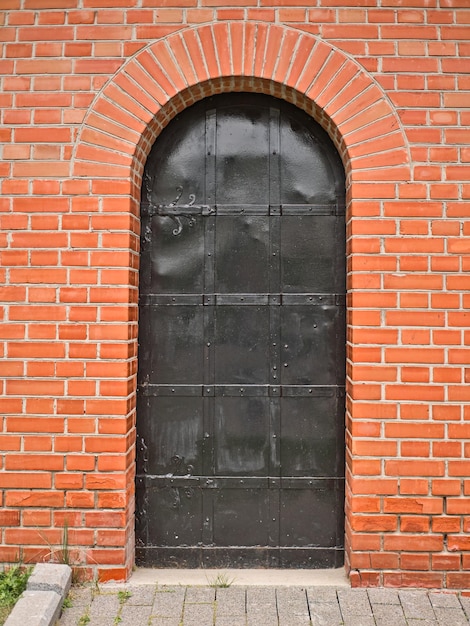 Old metal arch type door in the red brick wall