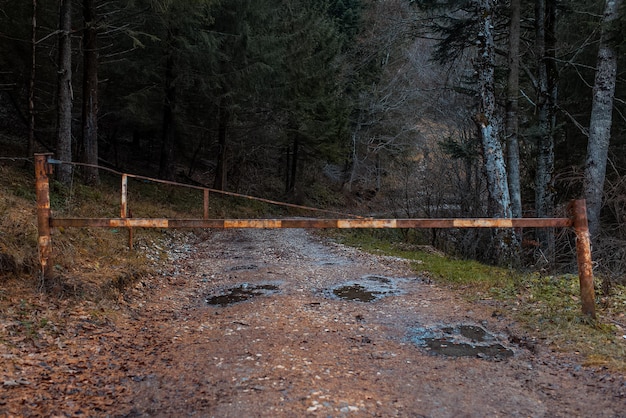 Old metal barrier gate closes the entrance in forest on country dirt road